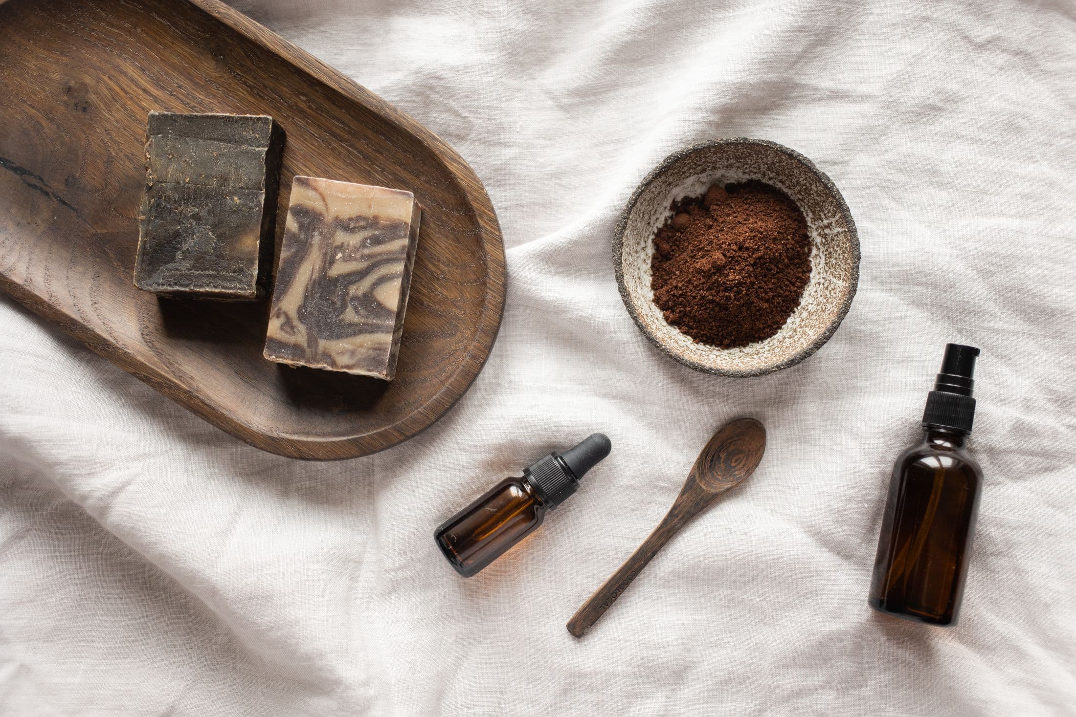 Savon noir, argile et huiles disposés sur lin