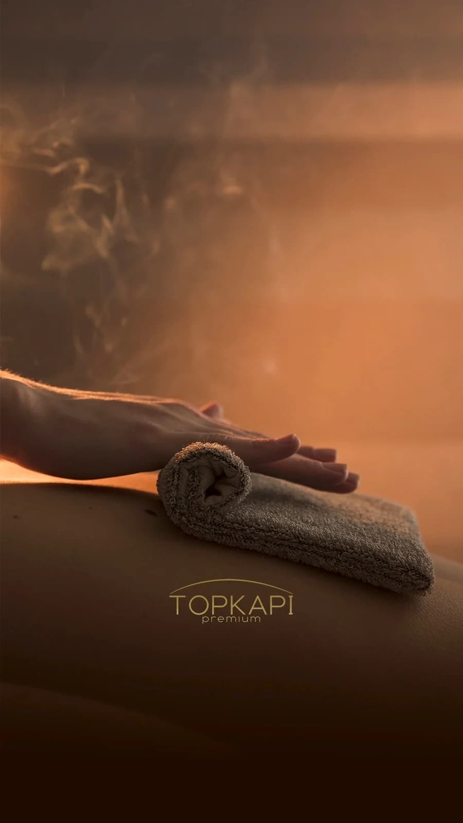Rituel de massage à la bougie, vapeur dorée dans la pénombre du hammam